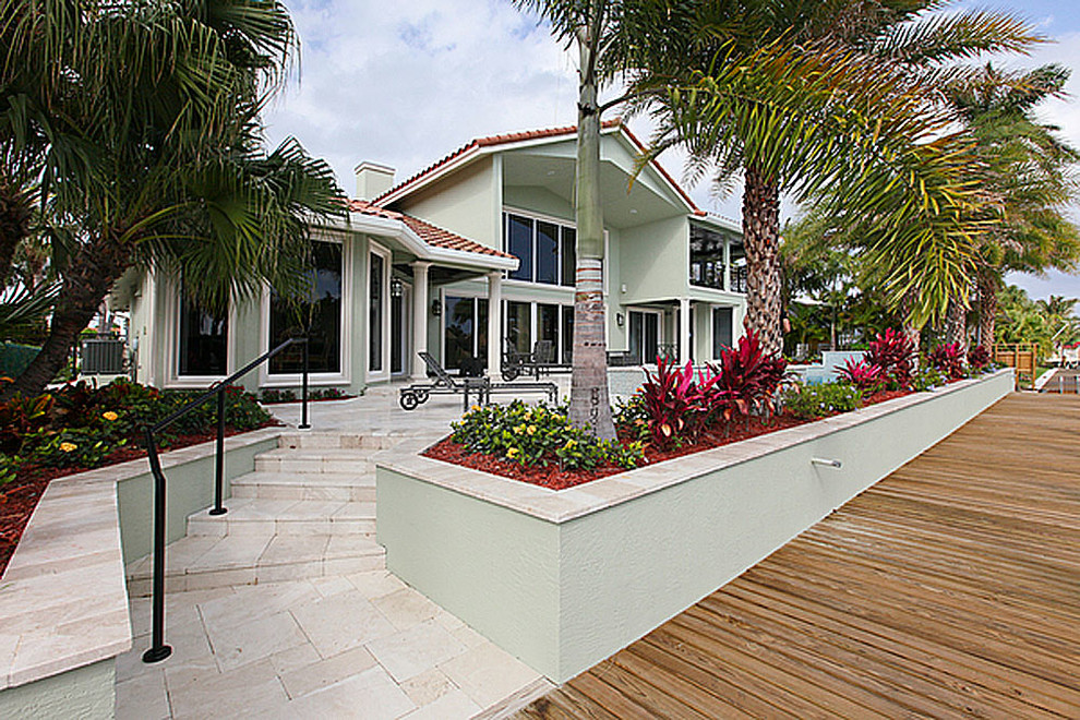 Design ideas for a large beach style backyard deck in Miami with a water feature and a roof extension.