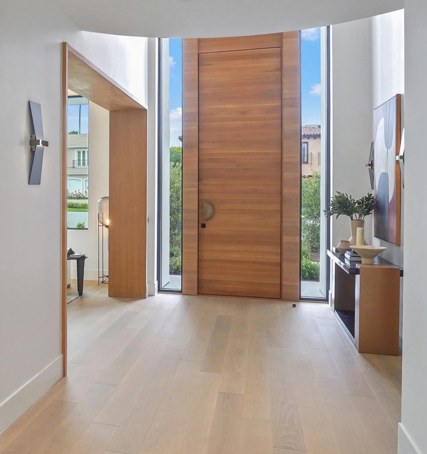 Photo of a large contemporary front door in San Francisco with white walls, light hardwood flooring, a pivot front door, a medium wood front door and brown floors.