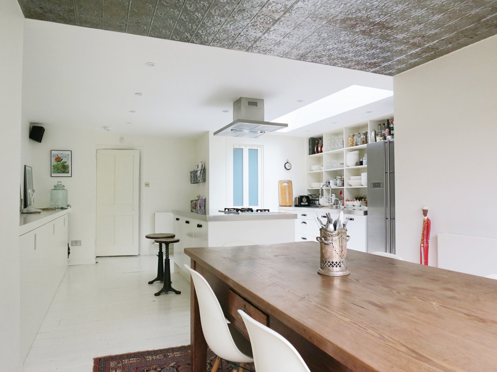 Eclectic kitchen/dining combo in London with white walls, painted wood floors and white floor.