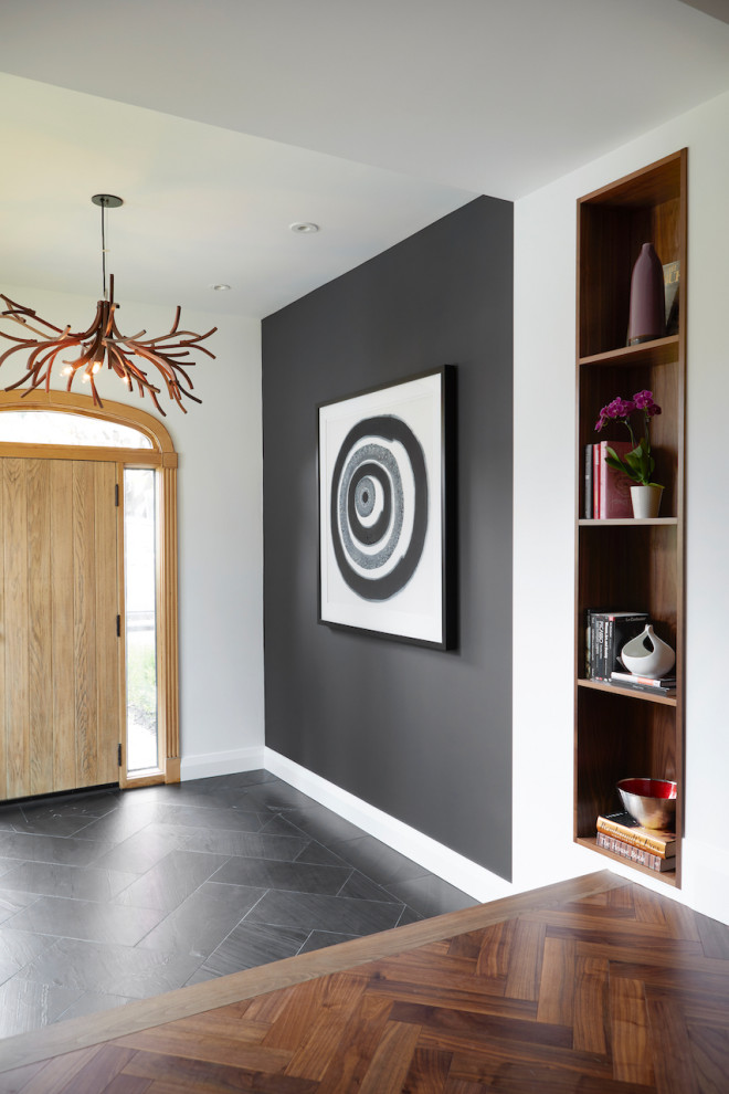 トロントにあるラグジュアリーな小さなシャビーシック調のおしゃれな玄関ロビー (白い壁、淡色木目調のドア、黒い床、ライムストーンの床、白い天井) の写真