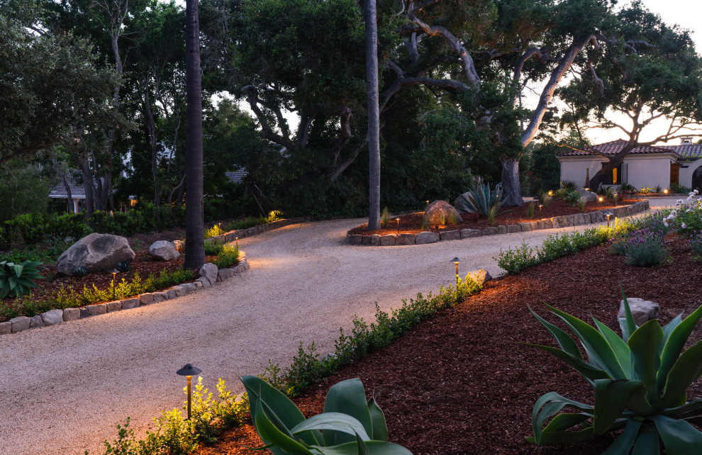 This is an example of a mediterranean front yard partial sun driveway in Santa Barbara with with lawn edging.