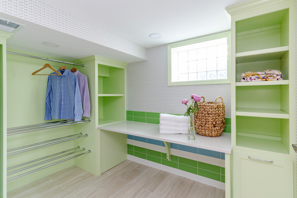 Photo of a transitional dedicated laundry room in Cincinnati with green cabinets, multi-coloured splashback, subway tile splashback, multi-coloured walls, laminate floors, a side-by-side washer and dryer and beige floor.