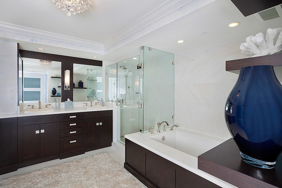 Corner shower - large transitional master white tile and marble tile beige floor corner shower idea in Miami with a drop-in sink, white walls, dark wood cabinets, recessed-panel cabinets, solid surface countertops, a hinged shower door and white countertops