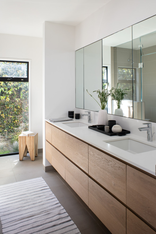 This is an example of a mid-sized modern master bathroom in San Francisco with flat-panel cabinets, light wood cabinets, an undermount tub, an open shower, a two-piece toilet, white tile, cement tile, white walls, ceramic floors, an undermount sink, quartzite benchtops, grey floor, a hinged shower door, white benchtops, a double vanity and a floating vanity.