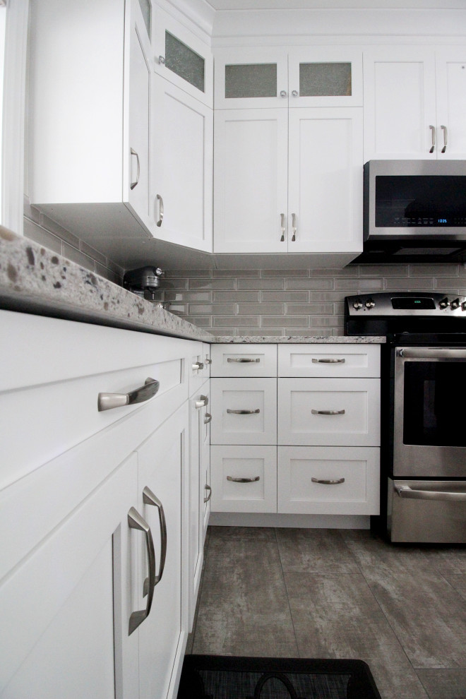 U-shaped kitchen photo with shaker cabinets, white cabinets, quartzite countertops, gray backsplash, subway tile backsplash, a peninsula and gray countertops