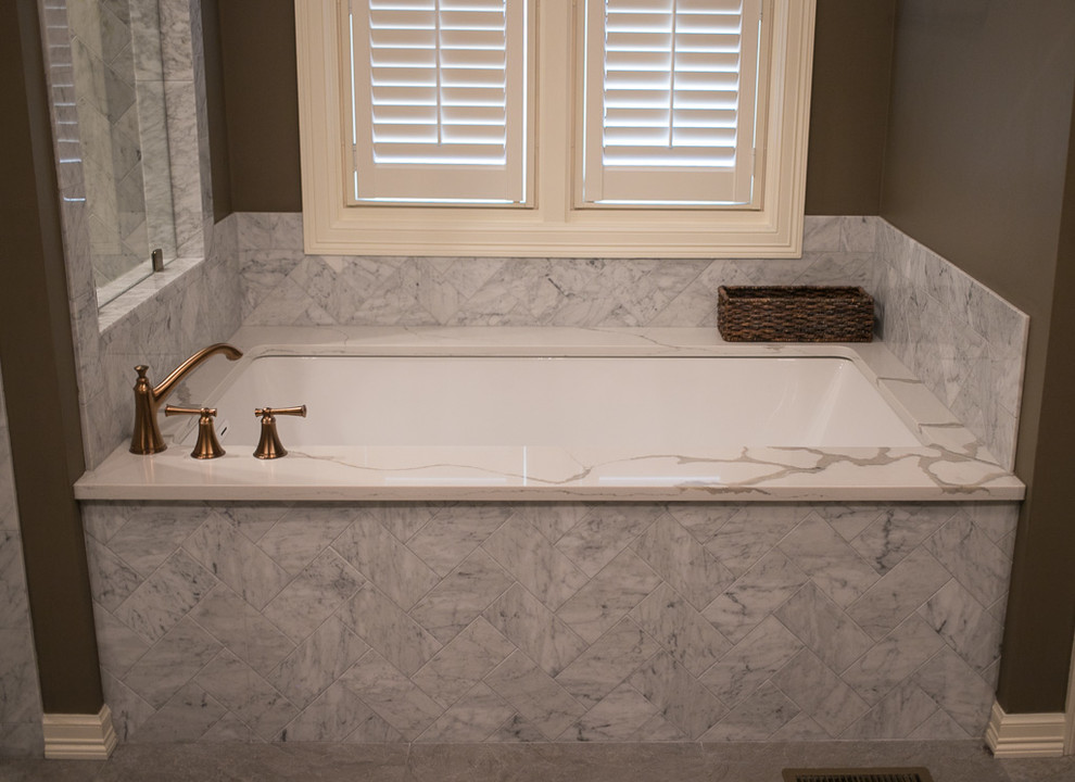 Large transitional master white tile and marble tile porcelain tile and gray floor corner shower photo with shaker cabinets, dark wood cabinets, an undermount tub, a one-piece toilet, brown walls, an undermount sink, quartz countertops, a hinged shower door and white countertops