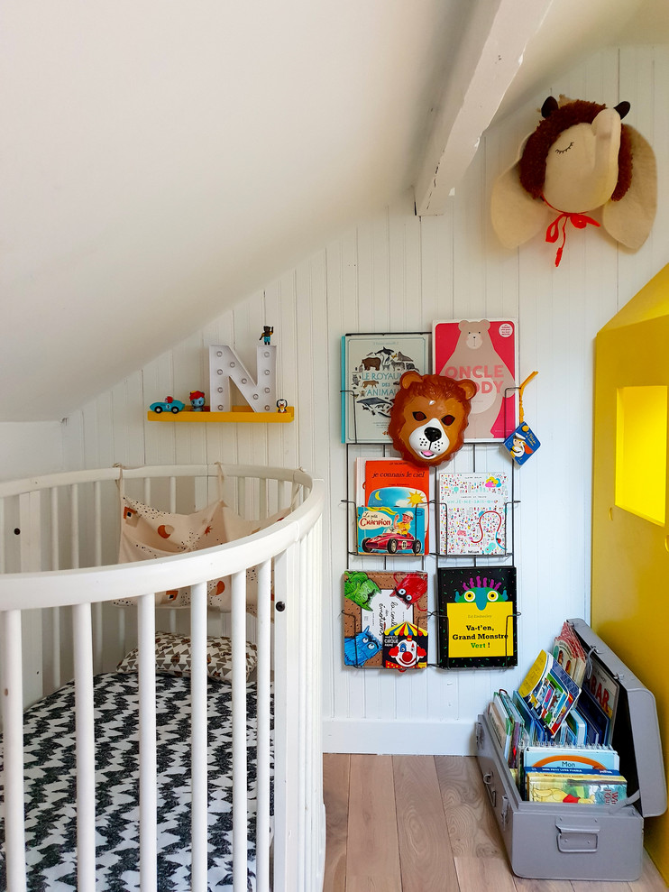 Photo of an eclectic nursery for boys in Paris with white walls, medium hardwood floors and brown floor.