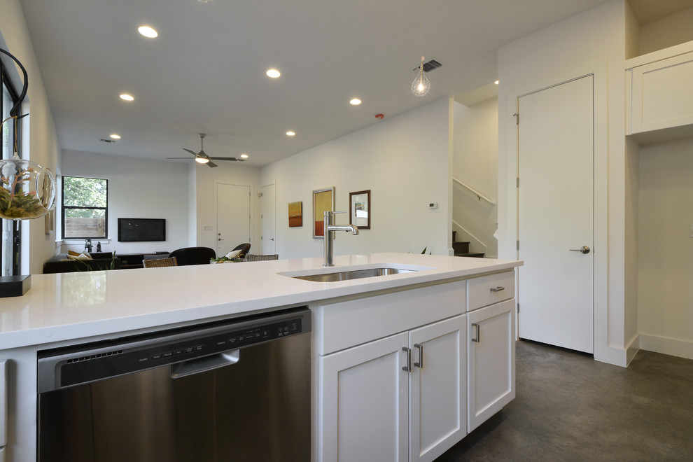 Kitchen - modern galley concrete floor kitchen idea in Austin with white cabinets, quartz countertops, black backsplash, subway tile backsplash and stainless steel appliances