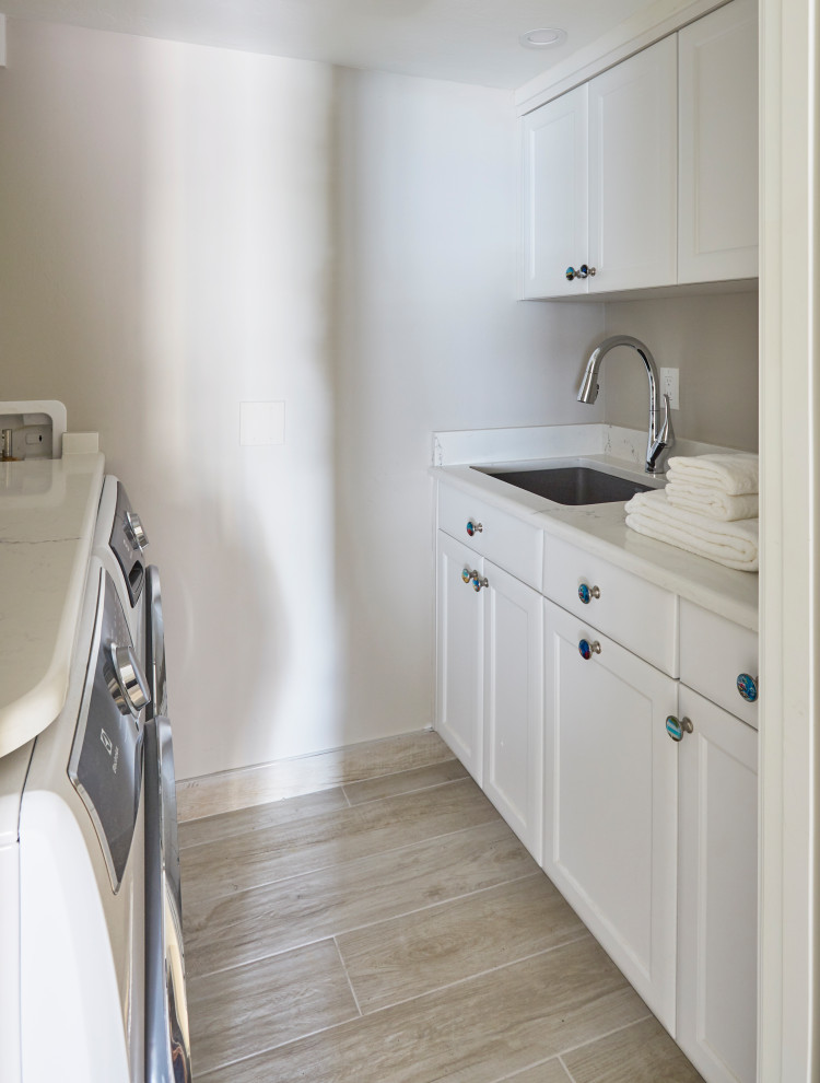 This is an example of a small transitional galley dedicated laundry room in Miami with an undermount sink, recessed-panel cabinets, white cabinets, quartz benchtops, white walls, porcelain floors, a side-by-side washer and dryer, grey floor and white benchtop.