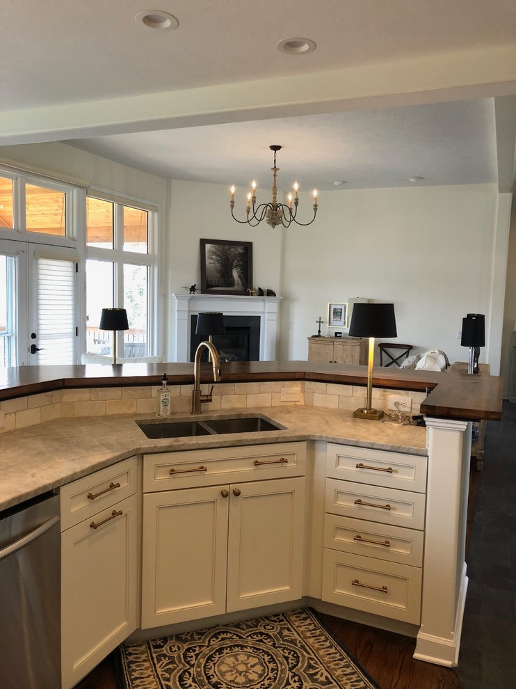 Open concept kitchen - large transitional dark wood floor and brown floor open concept kitchen idea in Omaha with an undermount sink, recessed-panel cabinets, beige cabinets, quartz countertops, beige backsplash, stone tile backsplash, stainless steel appliances, an island and beige countertops