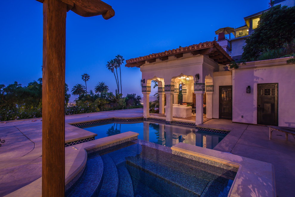 This is an example of a large mediterranean courtyard custom-shaped lap pool in Santa Barbara with stamped concrete and a hot tub.