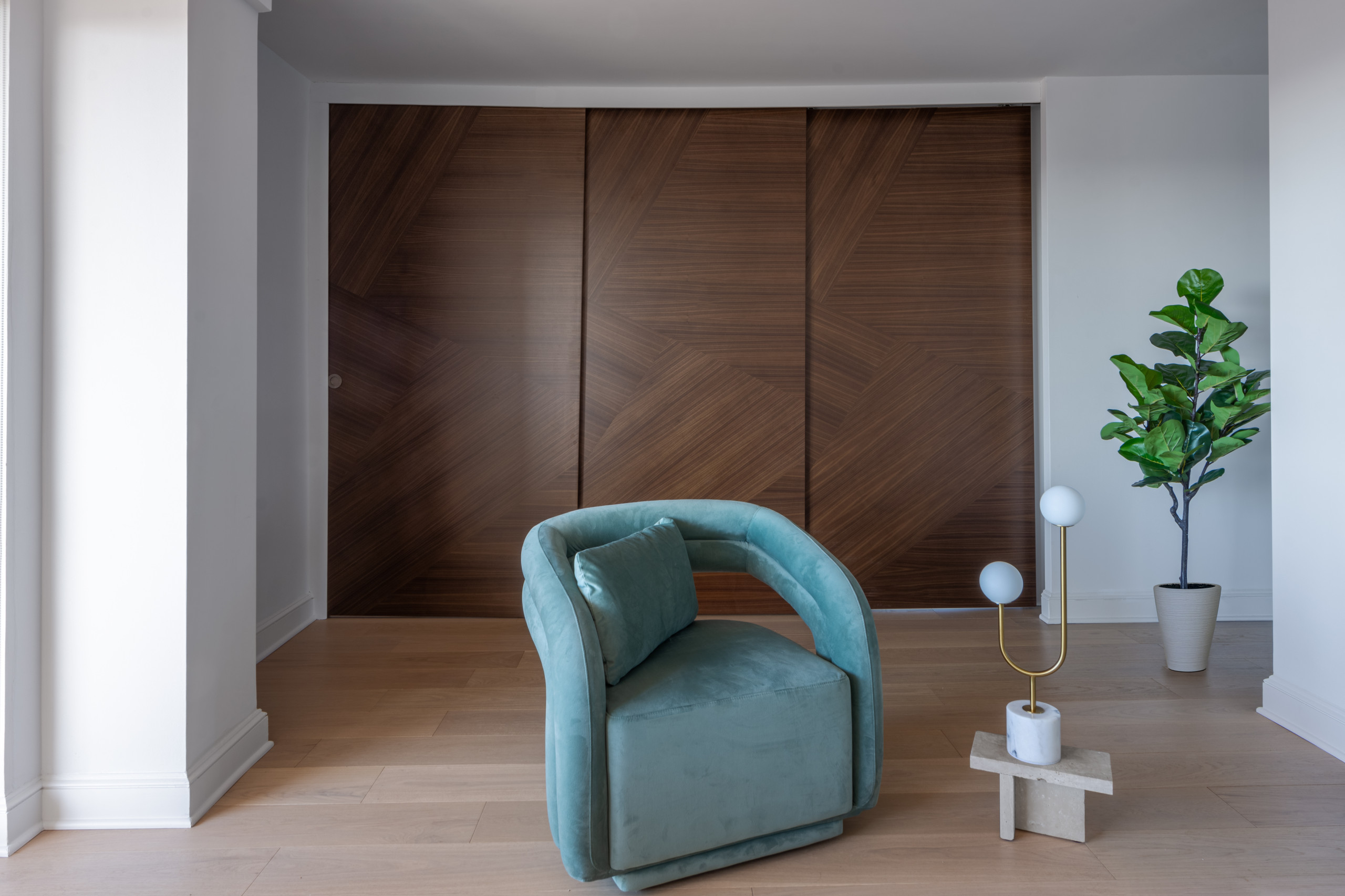 This space exudes modern elegance with a focus on clean lines and luxurious materials. The room features a stunning Italian made sliding door made of rich wood with a geometric pattern, creating a bol