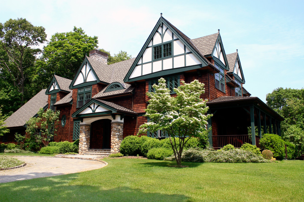 Large arts and crafts three-storey brown house exterior in New York with wood siding, a gable roof and a shingle roof.