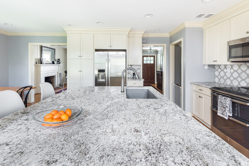 Example of a transitional medium tone wood floor kitchen design in Richmond with a drop-in sink, shaker cabinets, white cabinets, granite countertops, white backsplash, mosaic tile backsplash, stainless steel appliances and a peninsula