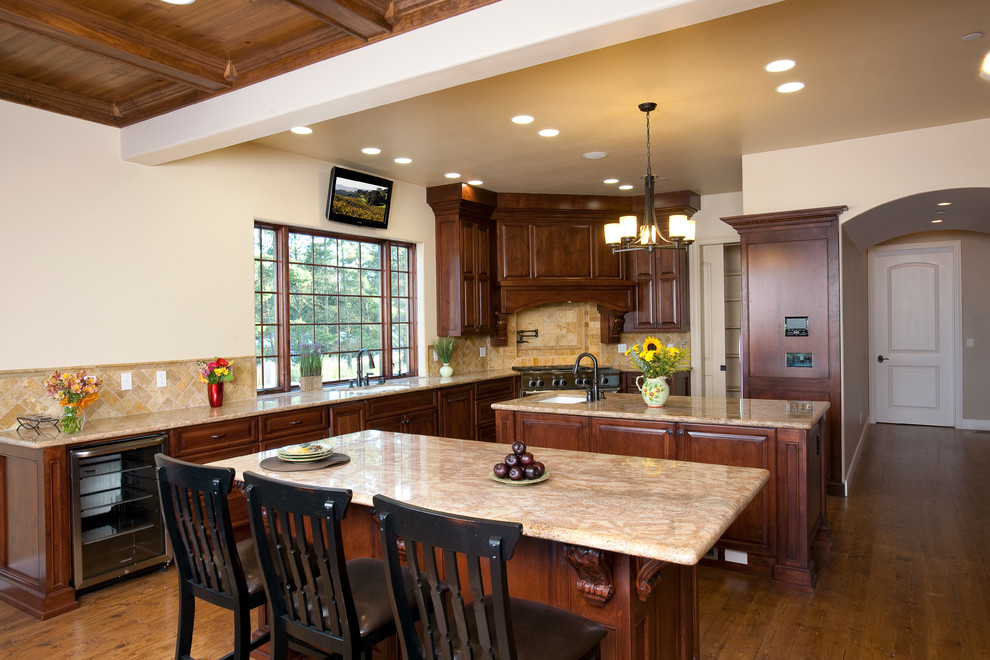 This is an example of a traditional kitchen in Santa Barbara with an undermount sink, raised-panel cabinets, medium wood cabinets, granite benchtops, beige splashback, stone tile splashback and stainless steel appliances.