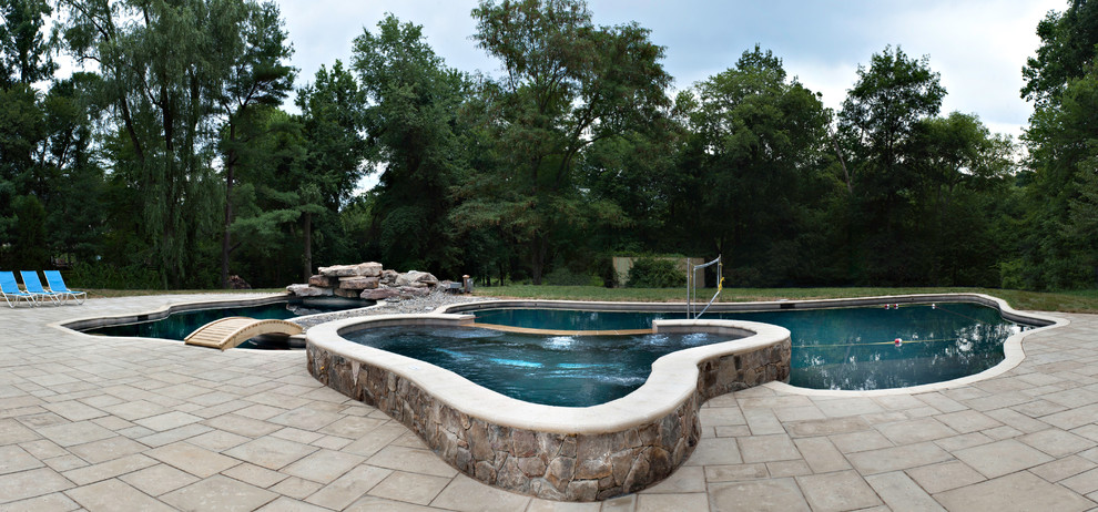 Large country backyard custom-shaped natural pool in DC Metro with a pool house and natural stone pavers.