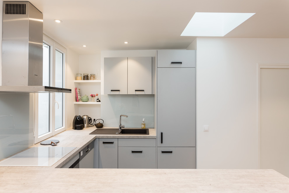 Photo of a mid-sized eclectic u-shaped open plan kitchen in Paris with no island, a drop-in sink, flat-panel cabinets, grey cabinets, laminate benchtops, white splashback, glass sheet splashback, stainless steel appliances, ceramic floors, grey floor and grey benchtop.