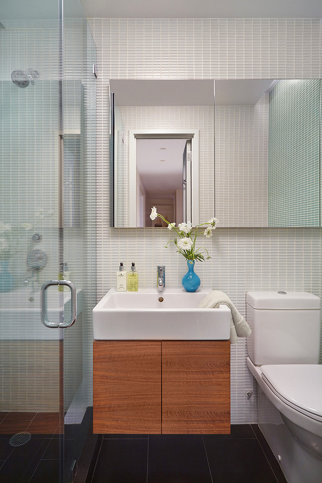 Mid-sized contemporary 3/4 bathroom in New York with flat-panel cabinets, medium wood cabinets, a two-piece toilet, ceramic floors, an alcove shower, a wall-mount sink, black floor and a hinged shower door.