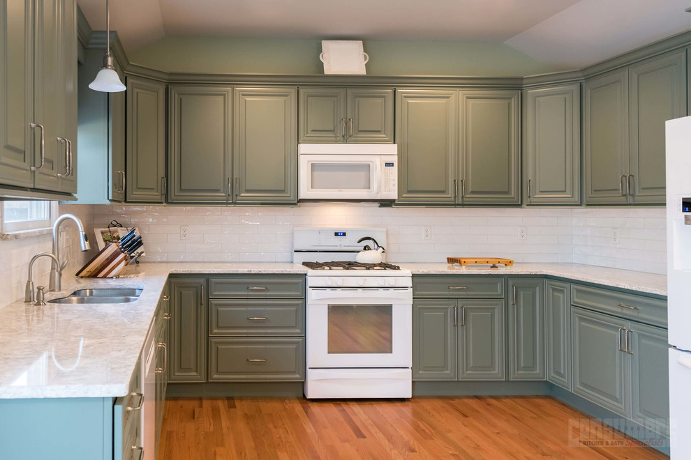 Mid-sized u-shaped eat-in kitchen in New York with an undermount sink, raised-panel cabinets, green cabinets, quartz benchtops, white splashback, ceramic splashback, white appliances, plywood floors, with island and beige floor.
