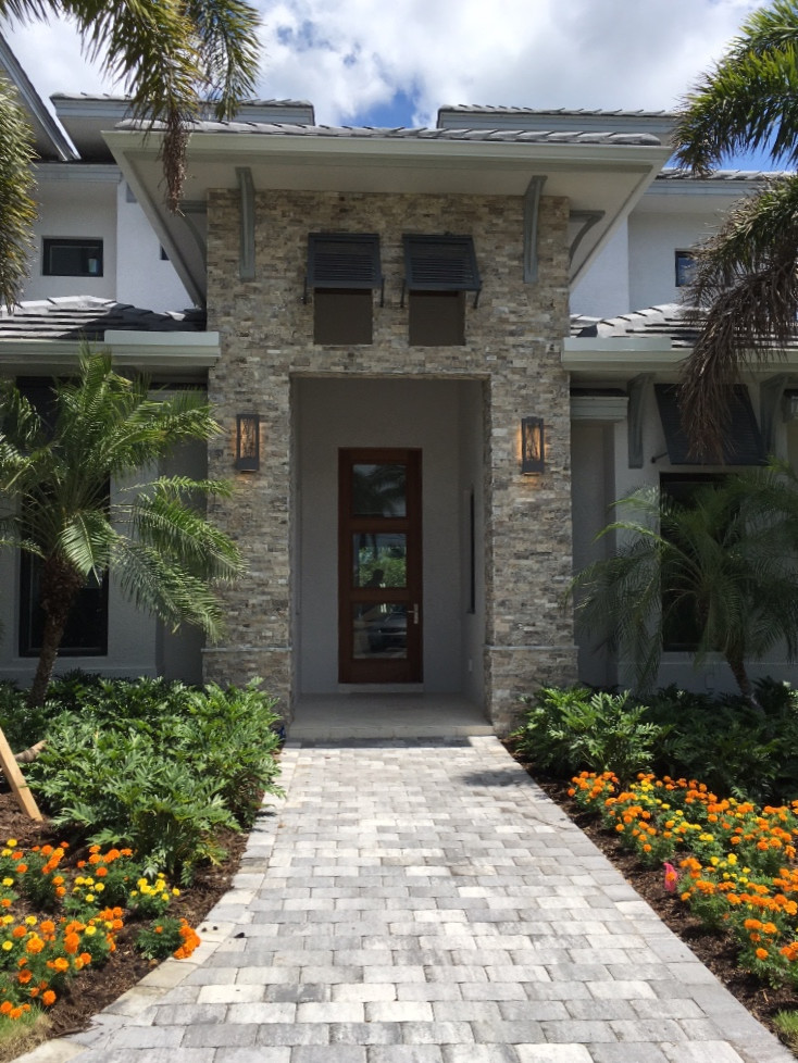 This is an example of a large contemporary two-storey white house exterior in Miami with mixed siding, a hip roof and a shingle roof.