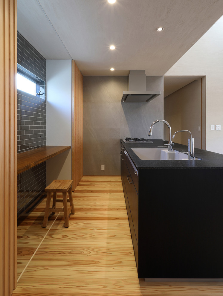 Idéer för mellanstora orientaliska linjära svart kök med öppen planlösning, med en undermonterad diskho, skåp i mörkt trä, bänkskiva i koppar, brunt stänkskydd, stänkskydd i porslinskakel, integrerade vitvaror, målat trägolv, en halv köksö och beiget golv