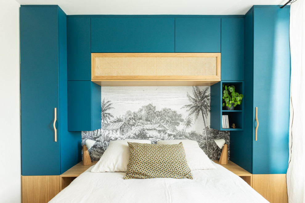 Imagen de dormitorio principal exótico pequeño con paredes azules, suelo de madera clara, suelo beige y papel pintado