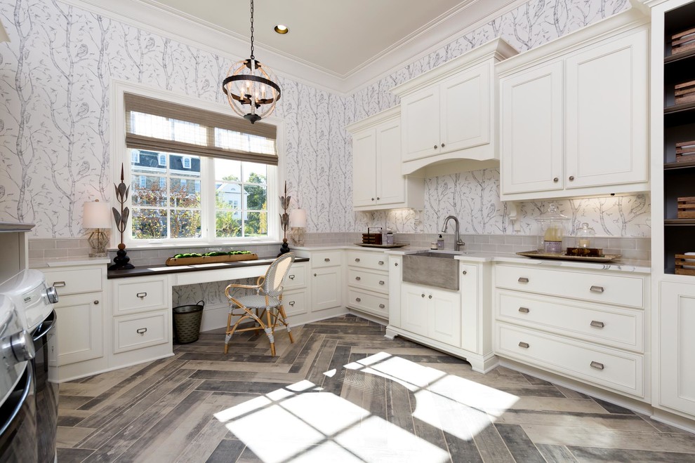 This is an example of a large country u-shaped utility room in Nashville with a farmhouse sink, white cabinets, granite benchtops, white walls, travertine floors, a side-by-side washer and dryer, grey floor and recessed-panel cabinets.