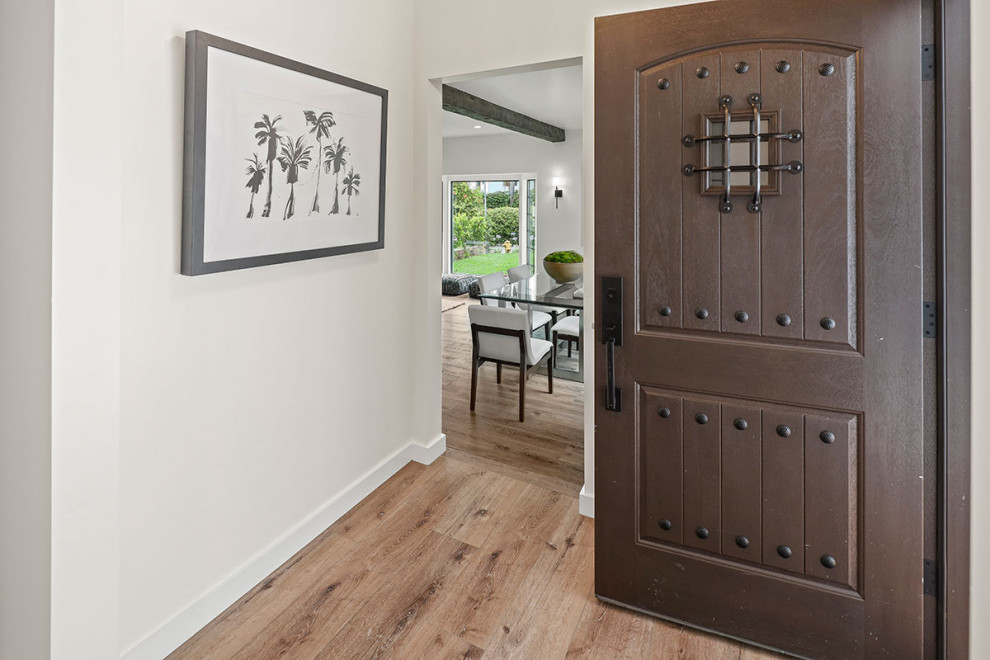 This is an example of a mid-sized transitional foyer in Los Angeles with white walls, medium hardwood floors, a single front door, a dark wood front door and brown floor.
