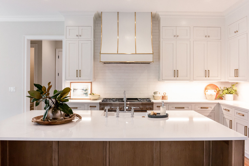 Large traditional l-shaped open plan kitchen in Atlanta with a submerged sink, beaded cabinets, white cabinets, engineered stone countertops, white splashback, metro tiled splashback, integrated appliances, medium hardwood flooring, an island, beige floors and white worktops.