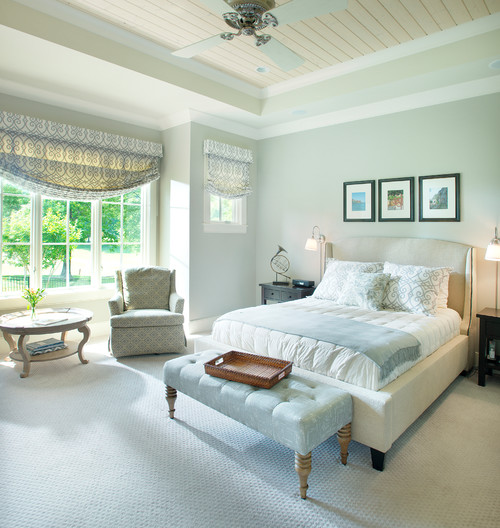 traditional bedroom with white platform bed and a white tufted bench at the end and a bay window