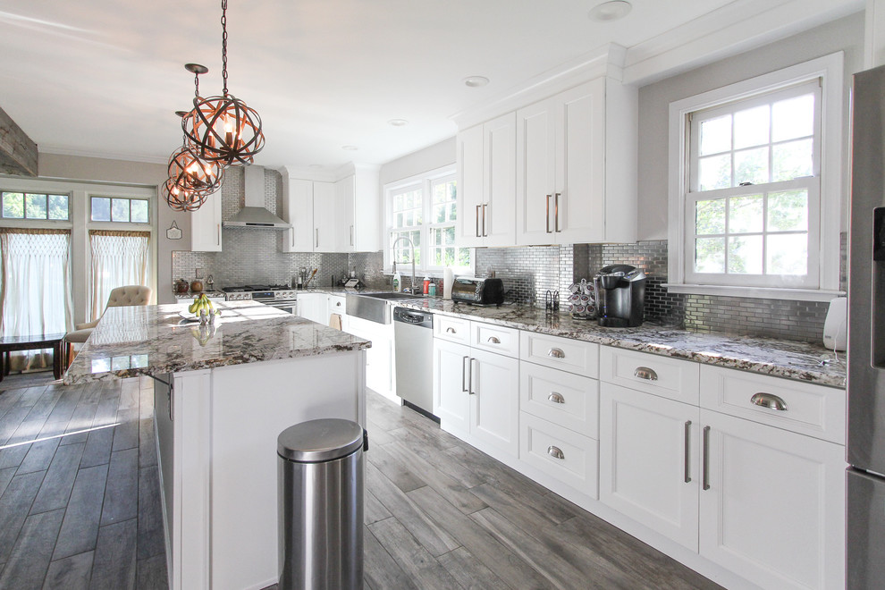 Expansive traditional l-shaped open plan kitchen in Philadelphia with a drop-in sink, shaker cabinets, white cabinets, marble benchtops, metallic splashback, subway tile splashback, stainless steel appliances, with island and multi-coloured benchtop.