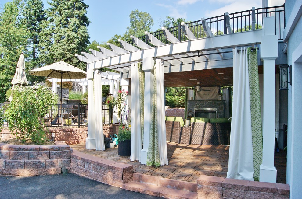Expansive contemporary backyard deck in New York with an outdoor kitchen and a pergola.