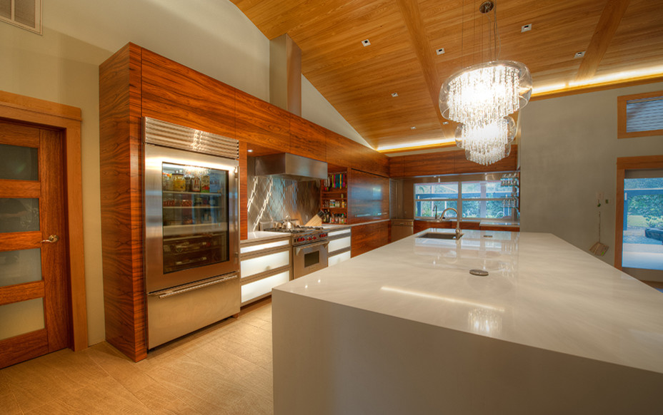 Photo of a mid-sized contemporary l-shaped eat-in kitchen in Miami with an undermount sink, flat-panel cabinets, medium wood cabinets, quartz benchtops, metallic splashback, stainless steel appliances, light hardwood floors, with island and beige floor.