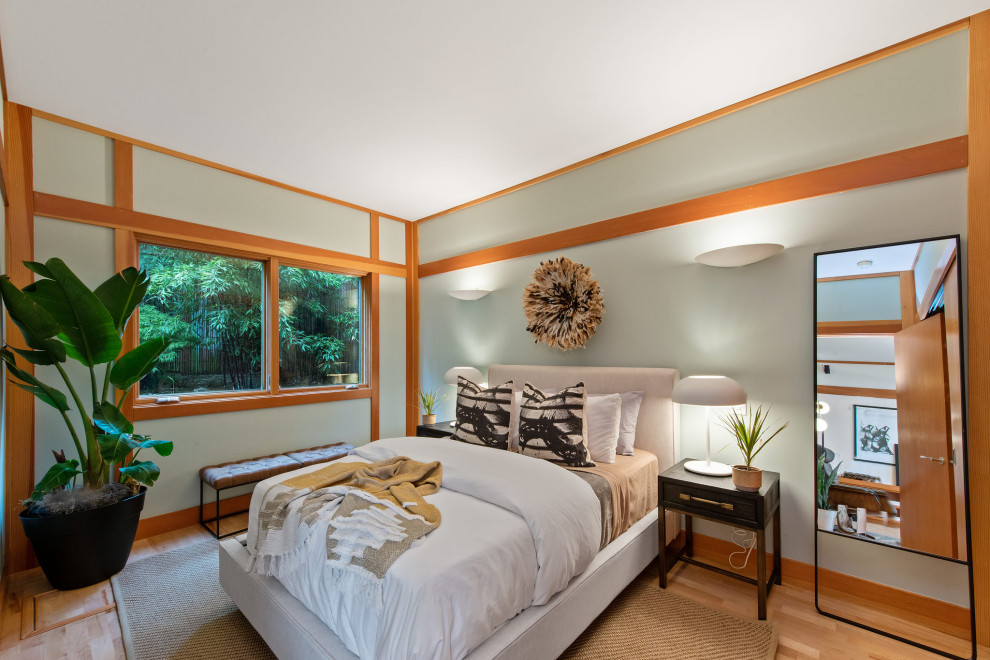 Design ideas for a mid-sized asian master bedroom in San Francisco with green walls, light hardwood floors, brown floor and wood walls.