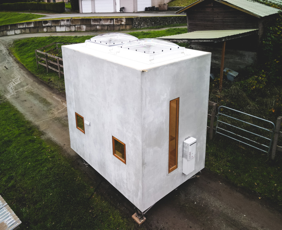 Idée de décoration pour une petite façade de Tiny House grise design en béton de plain-pied avec un toit plat et un toit blanc.