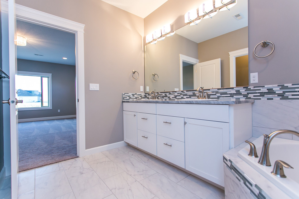 Example of a mid-sized transitional master multicolored tile and mosaic tile porcelain tile and white floor corner bathtub design in Seattle with shaker cabinets, white cabinets, a two-piece toilet, gray walls, granite countertops, a hinged shower door and a drop-in sink