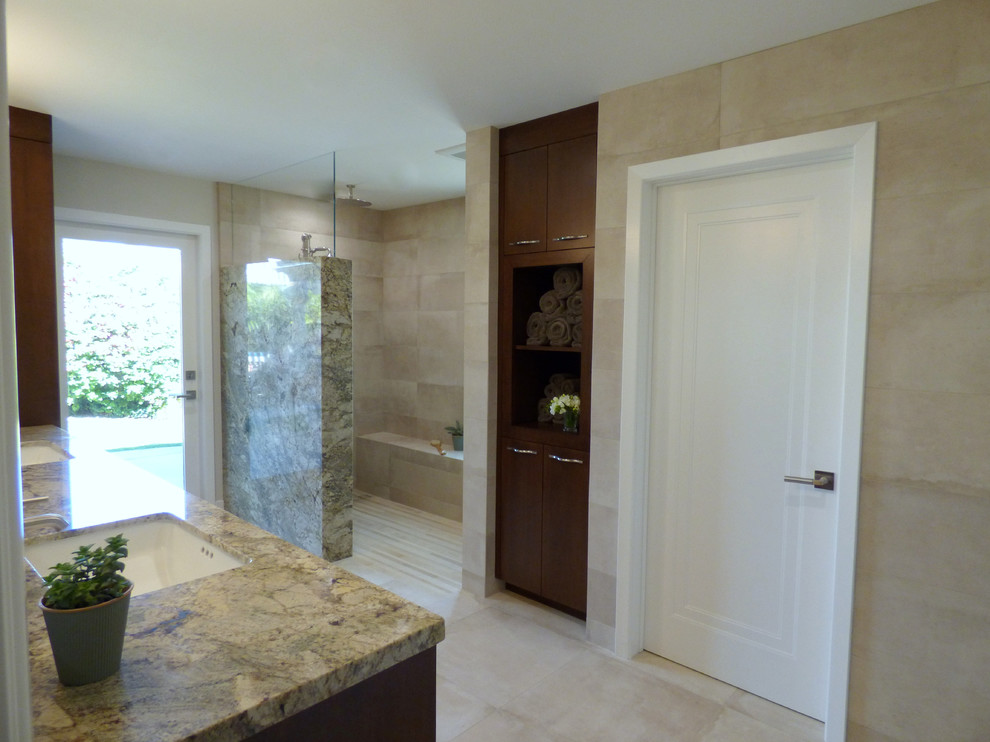 Large transitional master bathroom in Los Angeles with flat-panel cabinets, medium wood cabinets, a curbless shower, a one-piece toilet, beige tile, porcelain tile, beige walls, porcelain floors, an undermount sink and granite benchtops.
