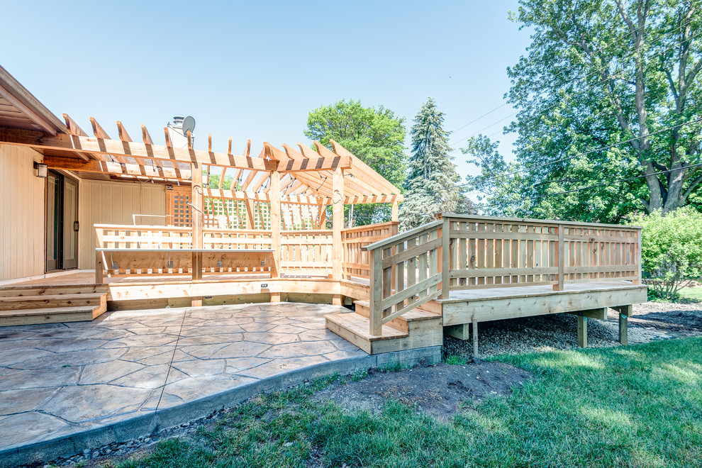 Example of a large transitional backyard deck design in Chicago with a pergola