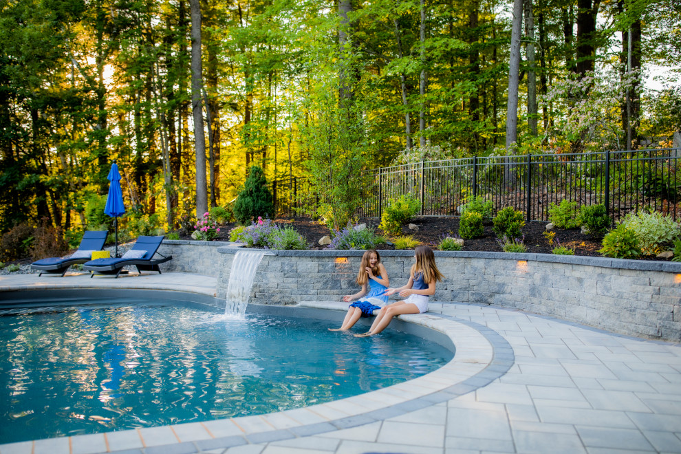 Aménagement d'un piscine avec aménagement paysager arrière classique en forme de haricot de taille moyenne avec des pavés en béton.
