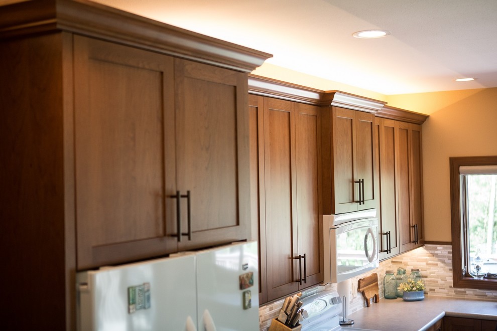 Example of a large transitional l-shaped light wood floor eat-in kitchen design in Cedar Rapids with a double-bowl sink, recessed-panel cabinets, medium tone wood cabinets, laminate countertops, multicolored backsplash, mosaic tile backsplash, white appliances and an island