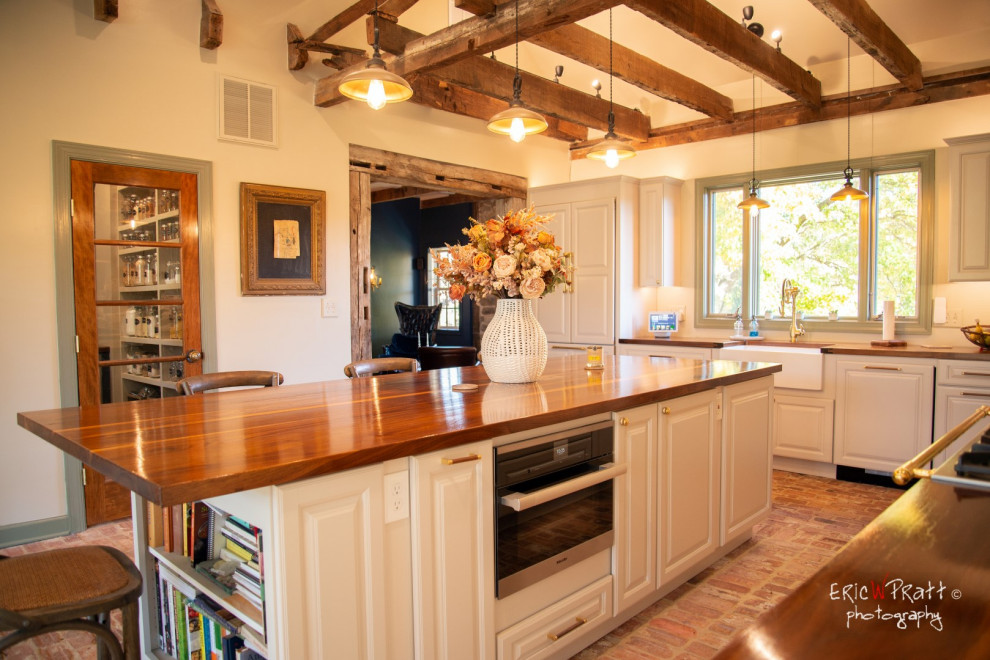 Esempio di una grande cucina rustica con lavello stile country, ante con bugna sagomata, ante bianche, top in legno, pavimento in mattoni e travi a vista