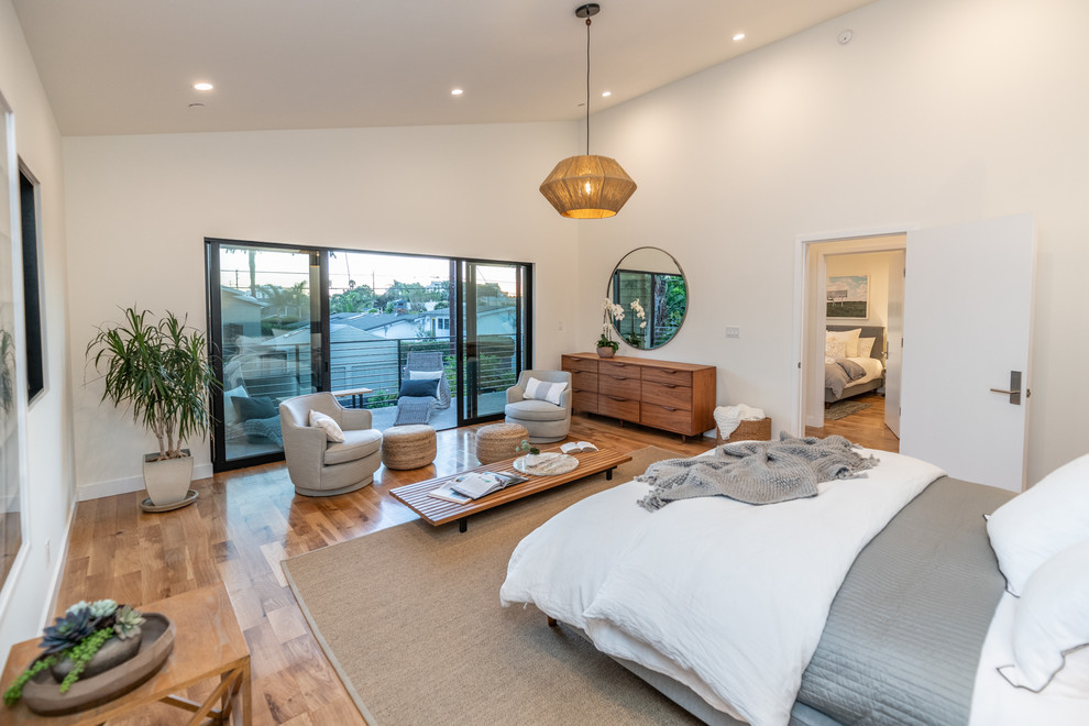 This is an example of a mid-sized midcentury master bedroom in Los Angeles with white walls, light hardwood floors, no fireplace and brown floor.