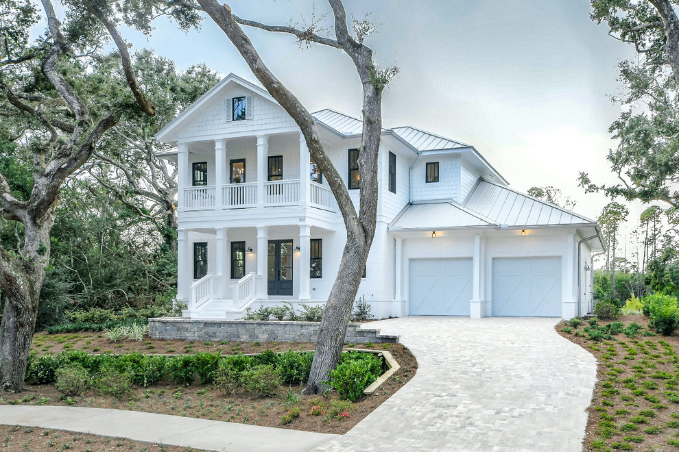 This is an example of a beach style two-storey white house exterior in Jacksonville with a hip roof and a metal roof.