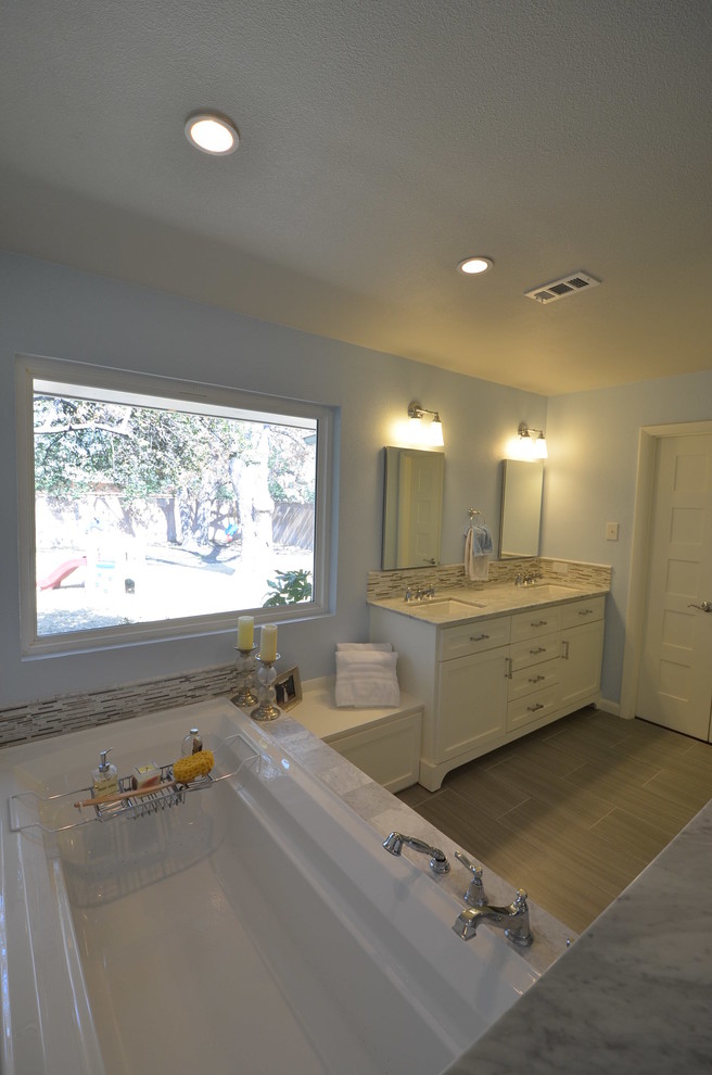 Inspiration for a mid-sized contemporary bathroom in Dallas with an undermount sink, flat-panel cabinets, white cabinets, marble benchtops, a drop-in tub, white tile, blue walls and porcelain floors.