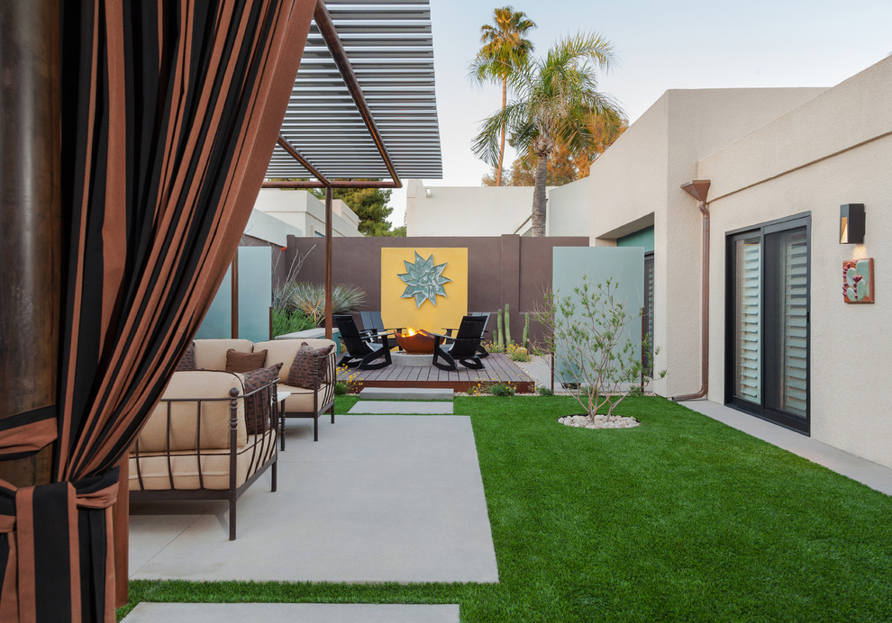 This is an example of a large modern backyard patio in Phoenix with a fire feature and a roof extension.