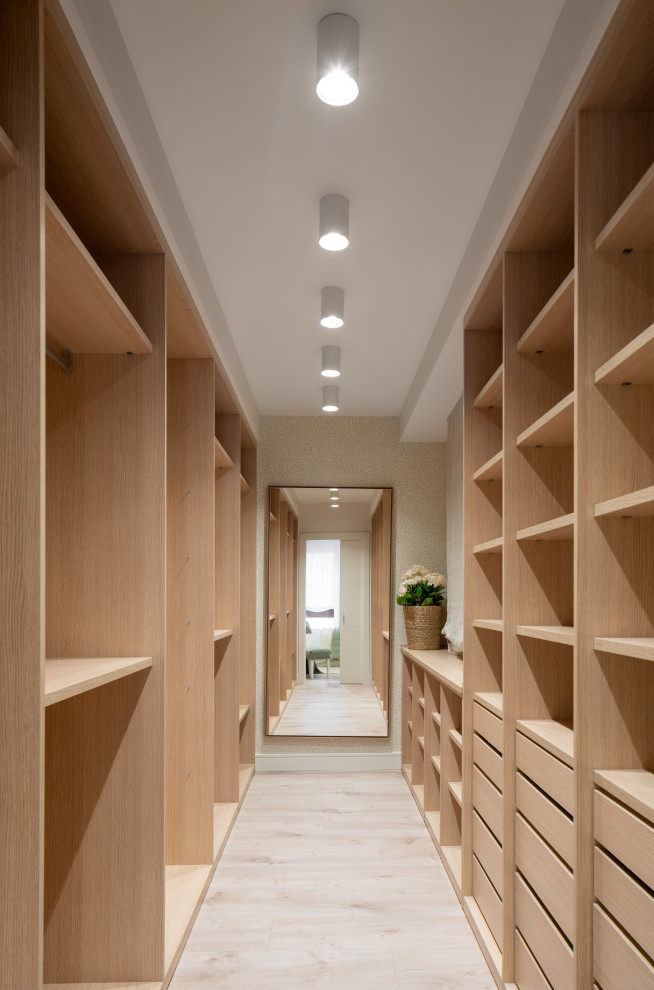 Ejemplo de vestidor unisex clásico renovado grande con armarios abiertos, puertas de armario de madera clara, suelo de madera clara y suelo beige