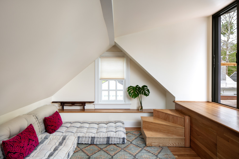 Bild på ett mellanstort sovloft, med vita väggar, mellanmörkt trägolv och brunt golv