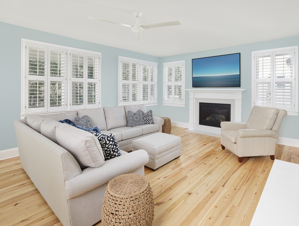 Mid-sized beach style family room in Charleston with blue walls, light hardwood floors, a standard fireplace, a stone fireplace surround and a wall-mounted tv.
