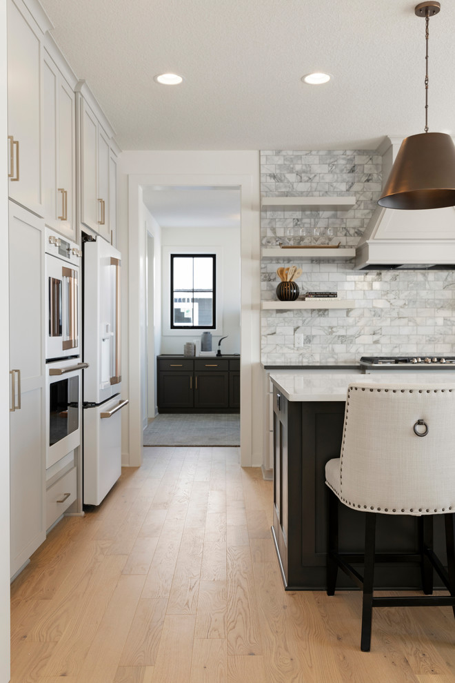 Design ideas for a transitional kitchen in Minneapolis with an undermount sink, quartzite benchtops, subway tile splashback, white appliances, light hardwood floors and with island.