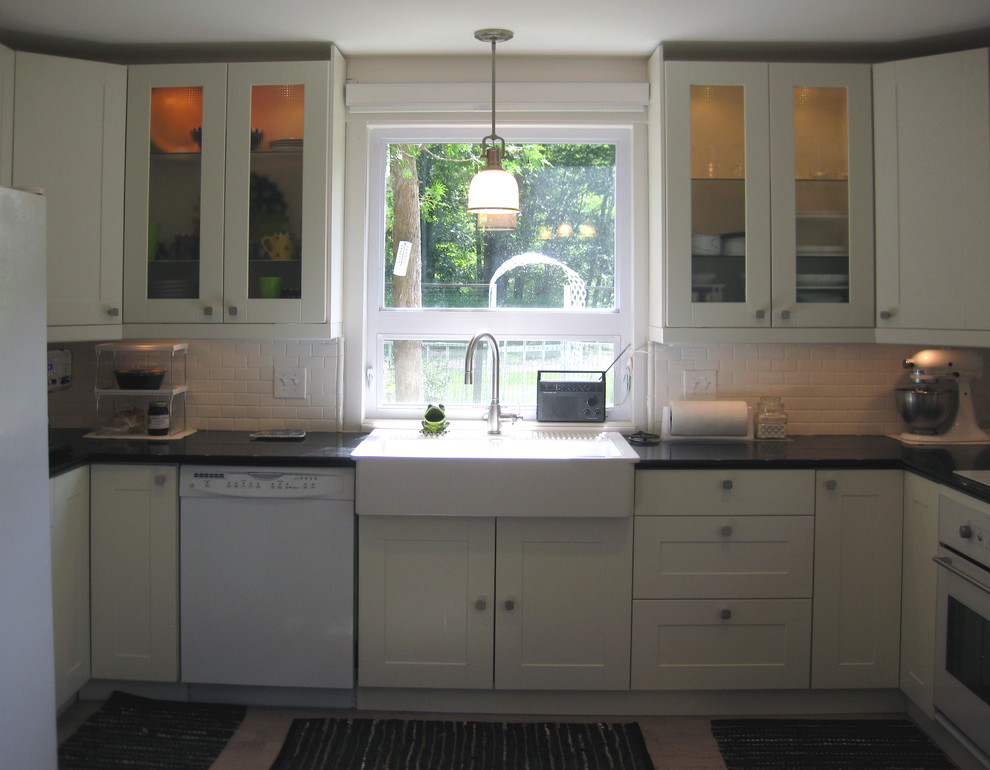 Example of a transitional u-shaped eat-in kitchen design in Milwaukee with a farmhouse sink, recessed-panel cabinets, white cabinets, quartz countertops, white backsplash, subway tile backsplash and white appliances